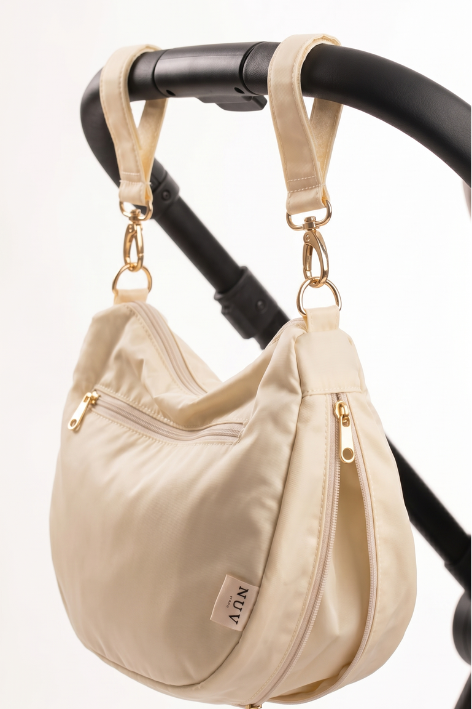 Luna Bag in Cream clipped to a stroller handle